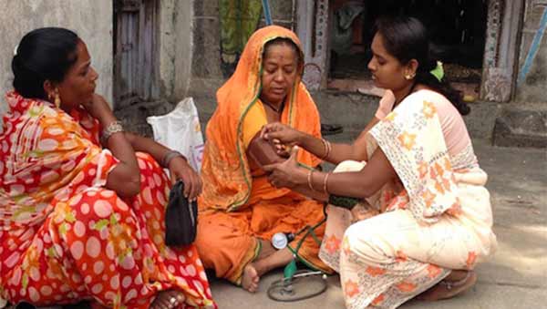 Photo of an Indian woman checking another woman's blood pressure