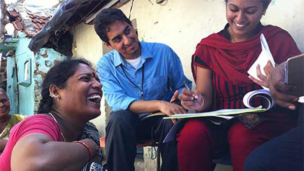 Photo of two Indian women and a man looking at papers and smiling